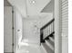 Hallway with white tile flooring, a staircase with dark wood handrail and a louvered door closet at 7210 8Th N Ave, St Petersburg, FL 33710