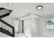 Hallway featuring a staircase with metal spindles, white tile floors, and natural light from the window at 7210 8Th N Ave, St Petersburg, FL 33710
