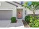 Close up of a charming front entrance with a wreath, green bushes, and a paved walkway at 7331 Canterbury Bells Ct, Tampa, FL 33619
