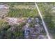 Aerial view of a property with a house and outbuildings surrounded by wooded areas and open spaces at 9802 Eden Ave, Hudson, FL 34667