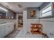 Bright bathroom featuring white tile, gray accent wall, floating wood shelves, and cabinet vanity at 9802 Eden Ave, Hudson, FL 34667