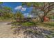 View of garden area in lot with large shade tree and house in the background at 9802 Eden Ave, Hudson, FL 34667