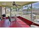 Enclosed sunroom with ceiling fan, seating, and views of the outdoor space featuring a grill and hammock at 9836 Rainbow Ln, Port Richey, FL 34668