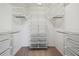 A white walk-in closet with customizable shelving and a neutral carpet, optimizing storage and organization at 10144 Arbor Run Dr # 157, Tampa, FL 33647