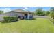 A spacious backyard featuring a well-maintained lawn, mature plantings and a covered patio with seating at 10868 Breaking Rocks Dr, Tampa, FL 33647