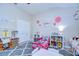 Charming bedroom featuring play kitchen, toddler bed, storage shelves, and gray patterned rug at 10868 Breaking Rocks Dr, Tampa, FL 33647