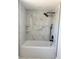 Modern bathtub shower with tiled walls and shelves and a black shower head at 11210 Yewtree Ave, Port Richey, FL 34668