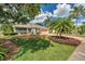 Beautifully landscaped front yard with lush green grass, mature trees, and a well-maintained garden at 1402 Bluewater Dr, Sun City Center, FL 33573