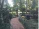 Charming brick path leading through a lush, landscaped yard to a quaint gated entrance at 1803 Longview Ln, Tarpon Springs, FL 34689