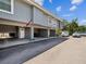 Charming two-story condo featuring a carport and white front door, set against a sunny sky with lush landscaping at 200 Meres Blvd # 26, Tarpon Springs, FL 34689