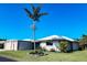 Charming single-story home featuring a well-manicured lawn and a large palm tree against a clear blue sky at 208 Villa Dr # 208, Osprey, FL 34229