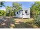 Backyard shed with a blue cross on the door, nestled in a grassy area surrounded by lush greenery at 2244 Glenmoor N Rd, Clearwater, FL 33764