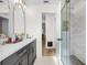 Bright bathroom with dual sinks, gold hardware, and a glass enclosed shower at 2244 Glenmoor N Rd, Clearwater, FL 33764