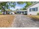 A winding driveway leads to a quaint white home with blue shutters, surrounded by lush greenery and mature trees at 2244 Glenmoor N Rd, Clearwater, FL 33764