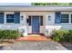 Inviting front entrance features a blue door, decorative lights, and potted plants, creating a warm welcome at 2244 Glenmoor N Rd, Clearwater, FL 33764
