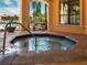 Relaxing hot tub with stone surround, set near a window and opening to views of palm trees and a resort-style pool at 2709 Via Cipriani # 522B, Clearwater, FL 33764