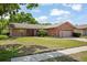 Charming single-story home featuring a brick facade, manicured lawn, and mature trees under a blue sky at 2859 Thistle N Ct, Palm Harbor, FL 34684