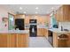 Functional kitchen featuring wood cabinetry, black appliances, and ample counter space for meal preparation at 2859 Thistle N Ct, Palm Harbor, FL 34684