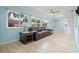 Bright living room with wood-look tile, a leather sofa, and plenty of natural light from the large windows at 2859 Thistle N Ct, Palm Harbor, FL 34684