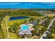 Aerial view of a luxury pool with a splash pad, palm trees, landscaping, and lake views at 2935 Winglewood Cir, Lutz, FL 33558
