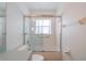 Bright bathroom featuring a tub-shower combo with glass door and white tiled walls at 301 Caloosa Palms Ct, Sun City Center, FL 33573