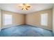 Spacious bedroom with a ceiling fan, two windows, neutral walls and blue carpet at 301 Caloosa Palms Ct, Sun City Center, FL 33573