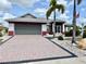 Charming single-story home with a paved driveway, well-manicured lawn, and mature palm trees at 301 Caloosa Palms Ct, Sun City Center, FL 33573