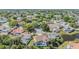 Aerial view of a pink house with mature trees, landscaping, and other homes in the neighborhood at 3136 Sandhill Dr, Holiday, FL 34691