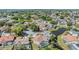 Aerial view of a pink house with mature trees, landscaping, other homes, and a pond in the neighborhood at 3136 Sandhill Dr, Holiday, FL 34691