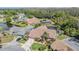 Aerial view of the pink house showing mature trees, a pond, landscaping, and other homes in the neighborhood at 3136 Sandhill Dr, Holiday, FL 34691