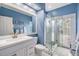Bright bathroom featuring a glass shower, white vanity, and blue walls at 3136 Sandhill Dr, Holiday, FL 34691