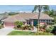 Charming one-story home with a manicured lawn, mature landscaping, and a striking turquoise front door at 3136 Sandhill Dr, Holiday, FL 34691