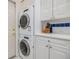 Convenient laundry room featuring a stackable washer and dryer and white cabinets at 3136 Sandhill Dr, Holiday, FL 34691