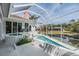 A luxurious screened-in outdoor pool with hot tub, overlooking a serene pond and landscaped backyard at 3136 Sandhill Dr, Holiday, FL 34691