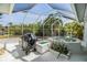 An inviting screened-in pool area, featuring a grill, hot tub, lush greenery, and serene backyard views at 3136 Sandhill Dr, Holiday, FL 34691