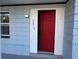 Attractive red front door with fresh white trim, the address, and blue siding on a well maintained home at 3615 Kingsbury Dr, Holiday, FL 34691