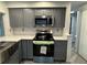 Well-lit kitchen with gray cabinetry, stainless steel appliances, and quartz countertops at 3615 Kingsbury Dr, Holiday, FL 34691
