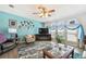 Comfortable living room featuring hardwood floors, soft armchairs, a modern TV, and bright, natural light at 37510 New Horizons Blvd, Zephyrhills, FL 33541