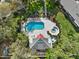 Aerial view of a home with a pool and spa surrounded by lush landscaping and well-manicured lawns at 4208 Edgewood Dr, Holiday, FL 34691