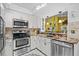 Galley style kitchen with stainless steel appliances, granite countertops, and white cabinetry at 4208 Edgewood Dr, Holiday, FL 34691