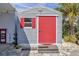 Storage shed with a vibrant red door, situated near a palm tree and lush greenery at 4851 W Gandy Blvd # B3 L8, Tampa, FL 33611