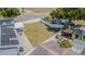 A large, fenced backyard features ample space, lush greenery, and an outdoor basketball court from an aerial view at 7015 Cobblewood Ct, Tampa, FL 33615