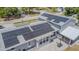 Aerial view showcases solar panels on a light grey home with a paved patio, basketball hoop, and screened enclosure at 7015 Cobblewood Ct, Tampa, FL 33615