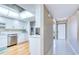 Modern kitchen with white cabinets, stainless steel appliances, and a tiled hallway at 7037 Sunset S Dr # 205, South Pasadena, FL 33707