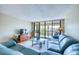 Comfortable living room with blue couch, wood floors, and sliding glass doors to the outdoor patio at 7037 Sunset S Dr # 205, South Pasadena, FL 33707