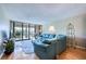 Cozy living room featuring a large blue couch, wood floors, and sliding glass doors to the balcony at 7037 Sunset S Dr # 205, South Pasadena, FL 33707