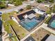 Aerial view of a home with solar panels, a screened-in pool, and a trampoline in the backyard at 7428 Bramblewood Dr, Port Richey, FL 34668