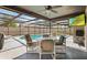 Screened-in pool is surrounded by outdoor seating with a ceiling fan above to keep cool at 7428 Bramblewood Dr, Port Richey, FL 34668