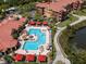 Aerial view of a community pool and patio with lounge chairs and red umbrellas at 2709 Via Cipriani # 522B, Clearwater, FL 33764