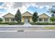 Exterior of the community clubhouse featuring a yellow facade, symmetrical design, and lush landscaping at 11309 Grand Park Ave, Riverview, FL 33578